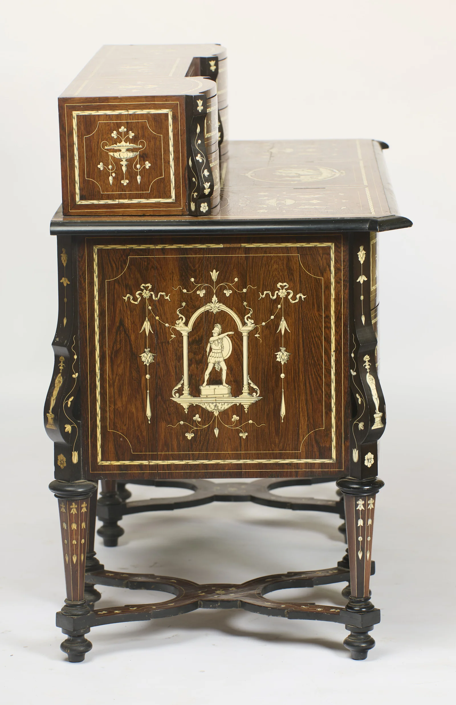 The end panel inlaid with a helmeted warrior holding a spear and shield within an arched niche, ribbon swags above, the superstructure and the shaped X-stretchers seen in profile.