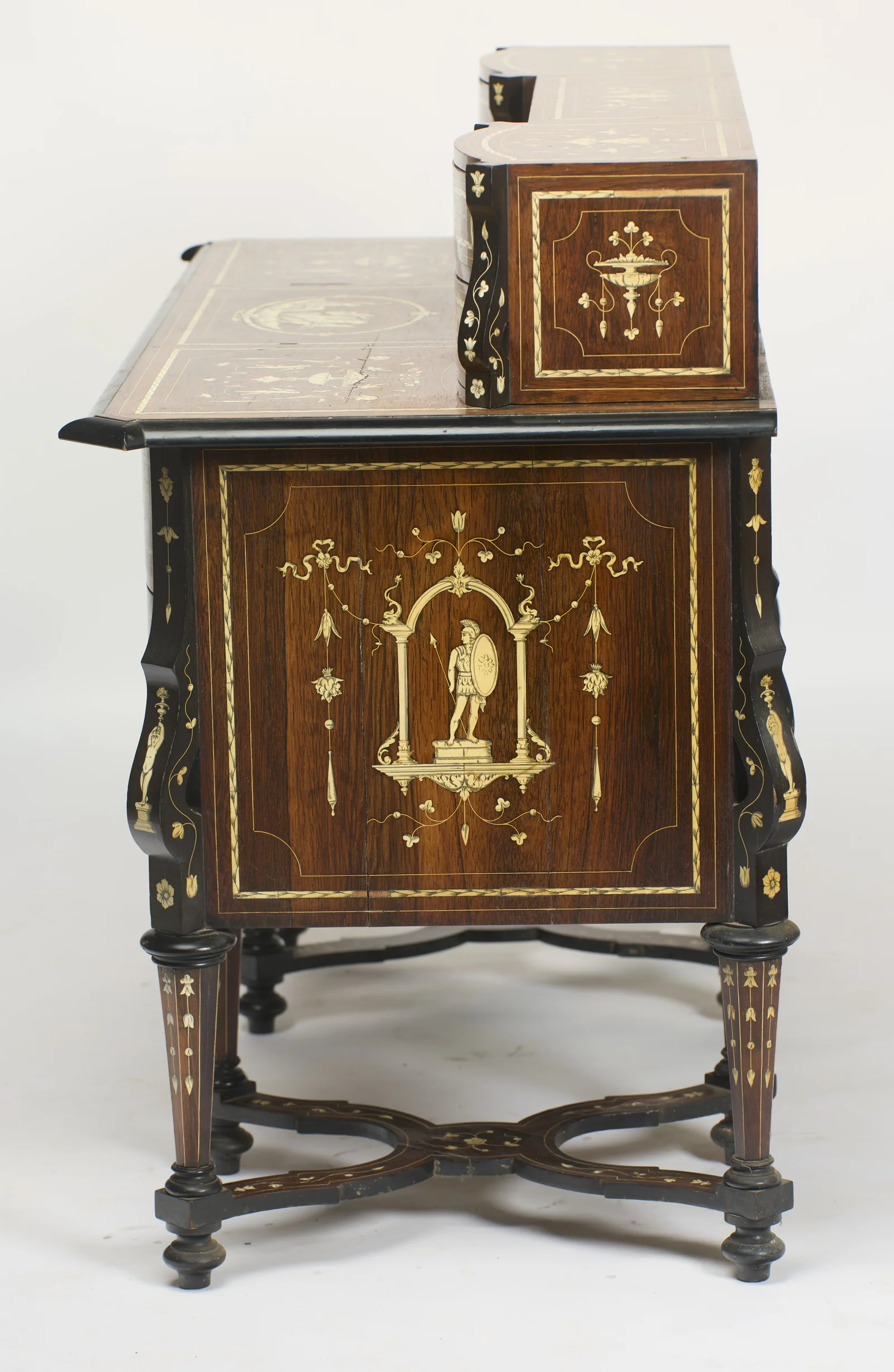 The same scheme on this end: an armed figure within a columned arch amid swags and pendants, with the end of the superstructure box inlaid with a pedestal urn; fine vertical shrinkage lines cross the panel.