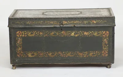 Swagged rows of domed studs around an oval keyhole escutcheon and ring pull, inside a painted flower border; small losses to the leather show along the lower edge of the lid.