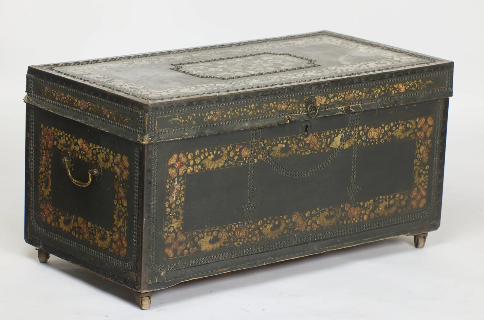 The hinged top and studded front seen together with the near end, its swan-neck handle hanging within a painted border of flowers and gilt foliage.