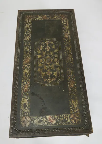 The lid in plan, a canted stud-bordered panel of painted gilt foliage at the centre within outer borders of flowers and close nailing; some dark staining to the leather.