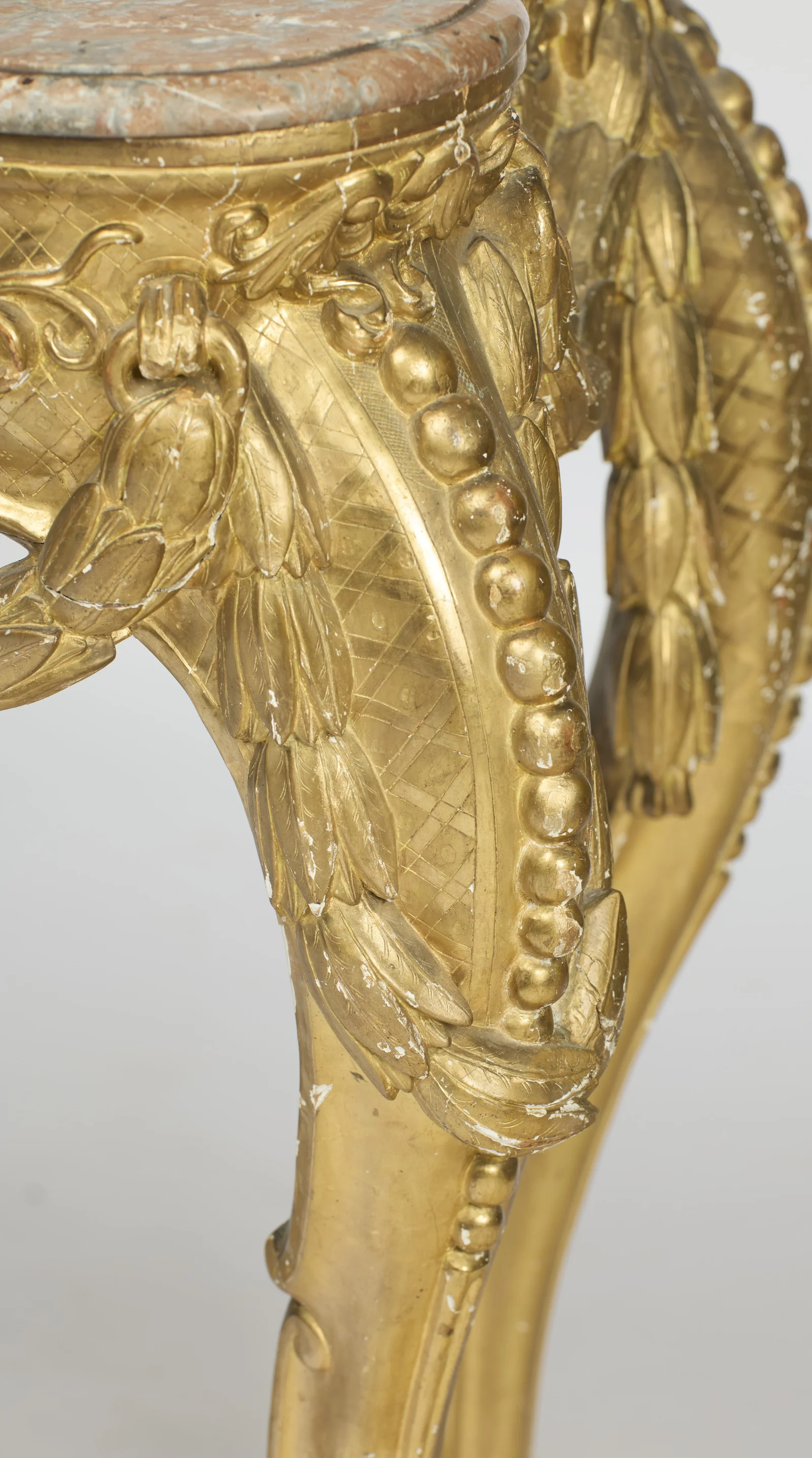 Laurel garlands fall across a bead-edged panel of engraved lattice, with husk trails running down the leg.