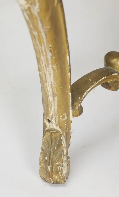 The plainer back foot with a leaf-carved tip, worn through along its outer face.