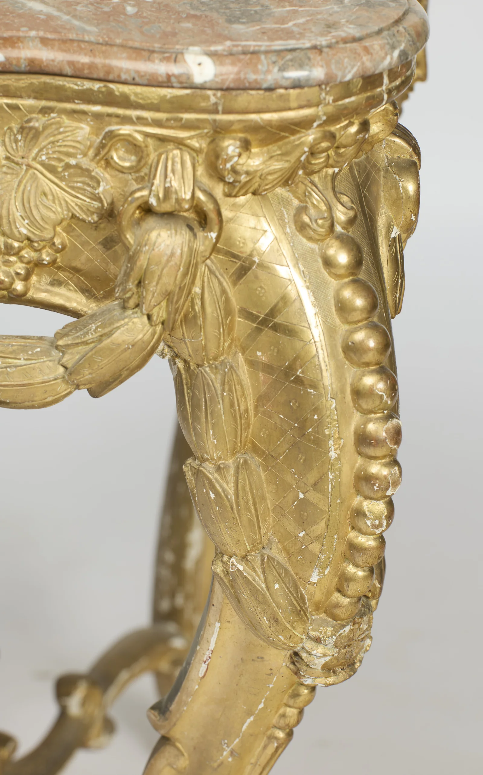 Tulip-like husks descend beside a run of gilt beading, framing the engraved lattice panel on the knee.