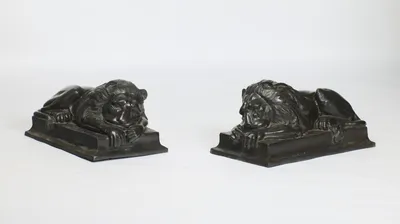 Both lions recumbent and asleep, each head sunk onto crossed forepaws, on rectangular plinths with moulded stepped edges.