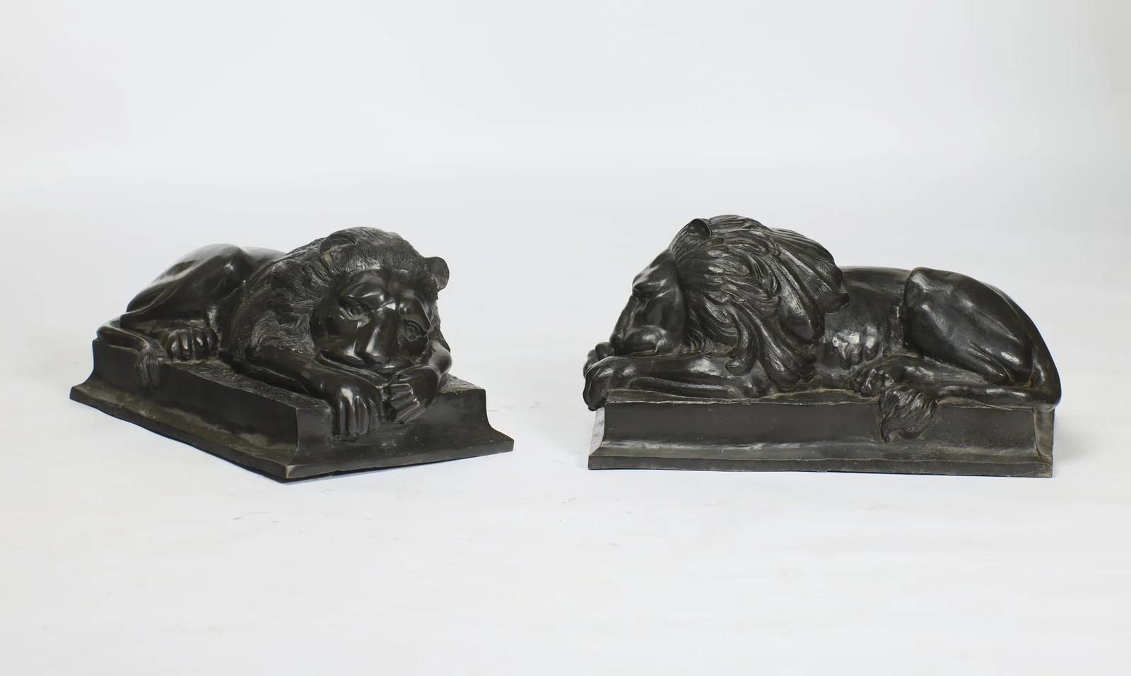 The pair seen at an angle, showing the depth of the plinths and the sweep of each mane over the shoulders.
