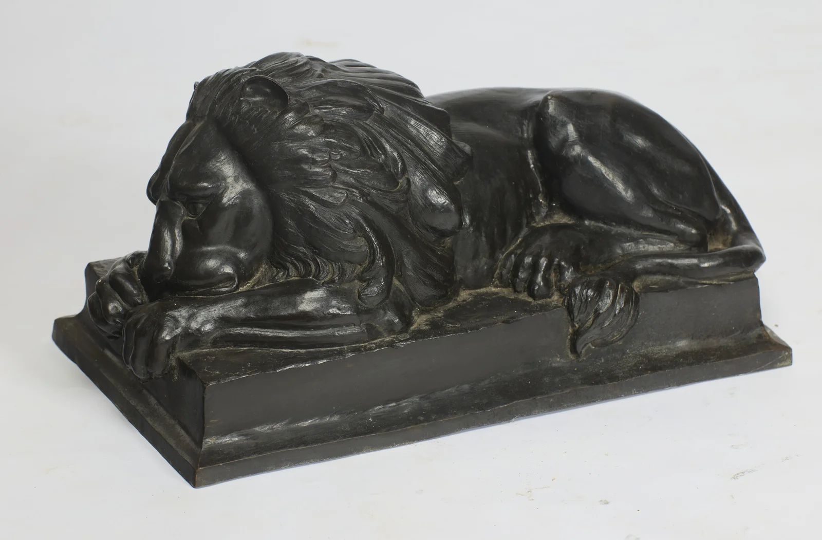 Deep flowing locks over the head and shoulder, the eye half closed beneath a heavy brow, the muzzle sunk onto the forepaws.