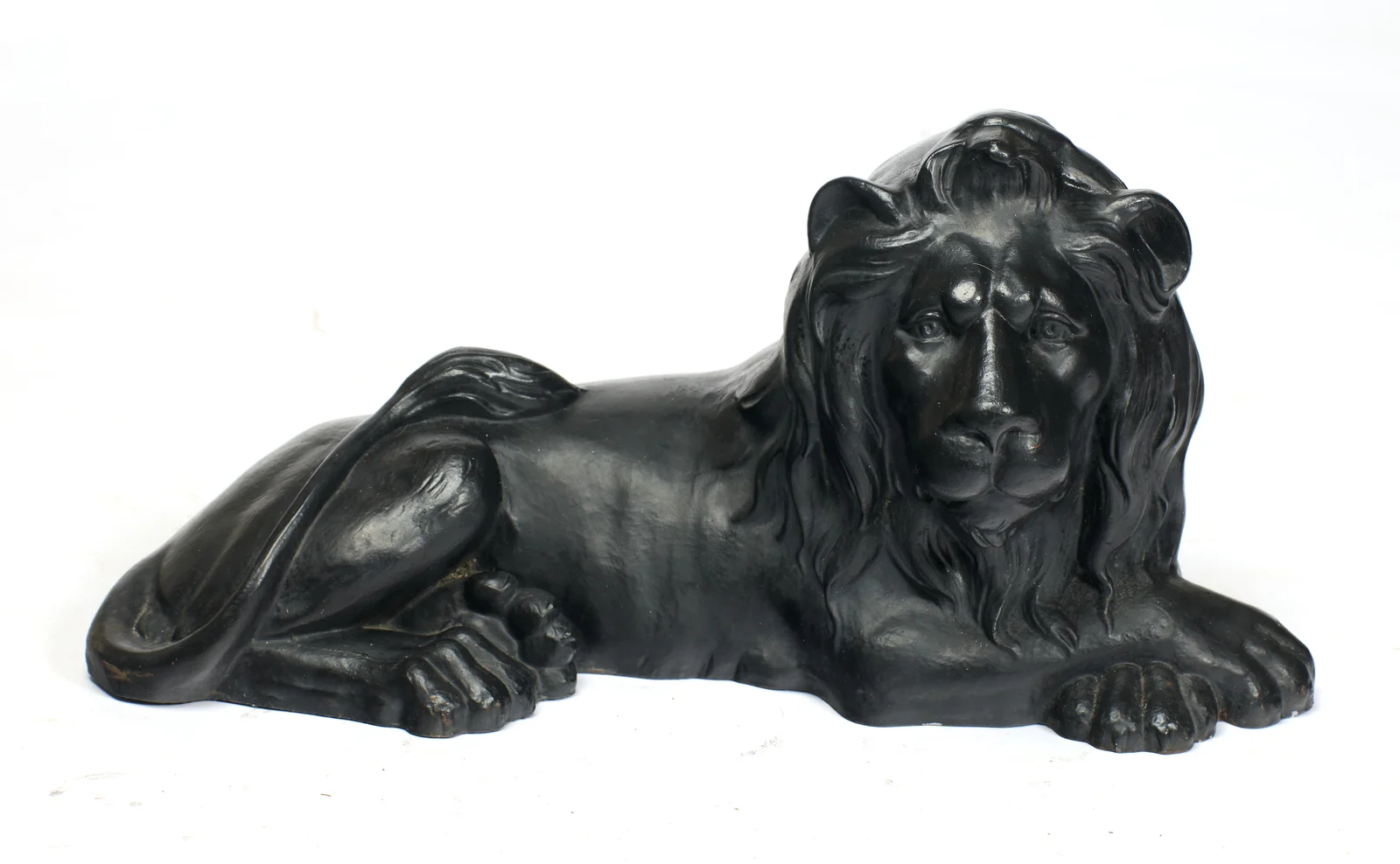 A different lion, recumbent with head erect and alert, lying directly on the ground with no plinth.