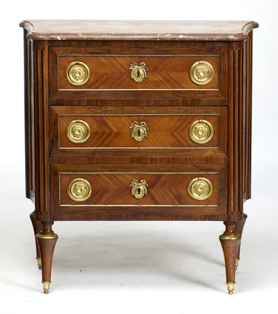 Three long drawers, each with a pair of pressed rosette ring handles and a ribbon-crested escutcheon, framed in beaded gilt-metal beneath the moulded marble top.