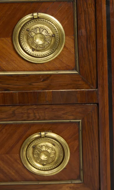 The rounded projecting corner of the marble sits directly over the inlaid corner flutes, with two rosette handles below.