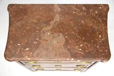 Seen from above, the reddish-brown slab with white veining and fossil-like inclusions, shaped to rounded projecting corners; surface wear and pale fills are visible.