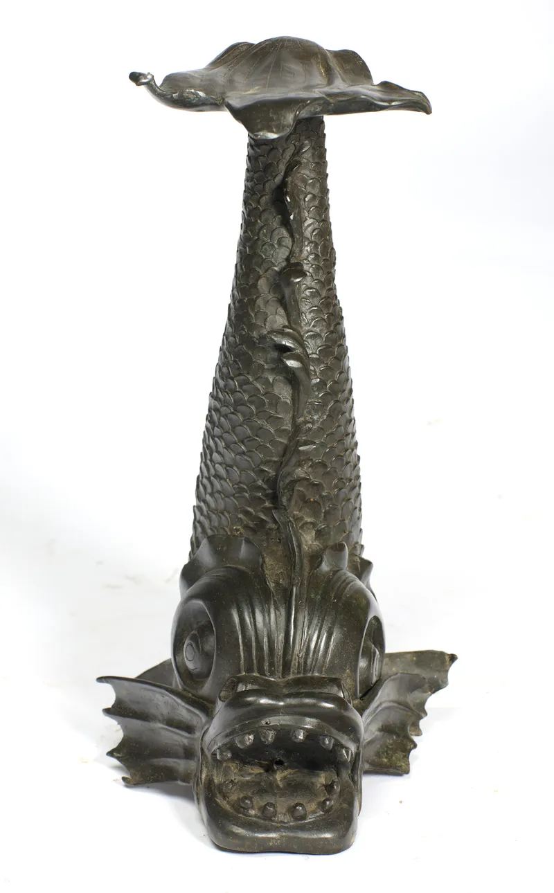 A large patinated metal grotesque dolphin with leaf-form dish top